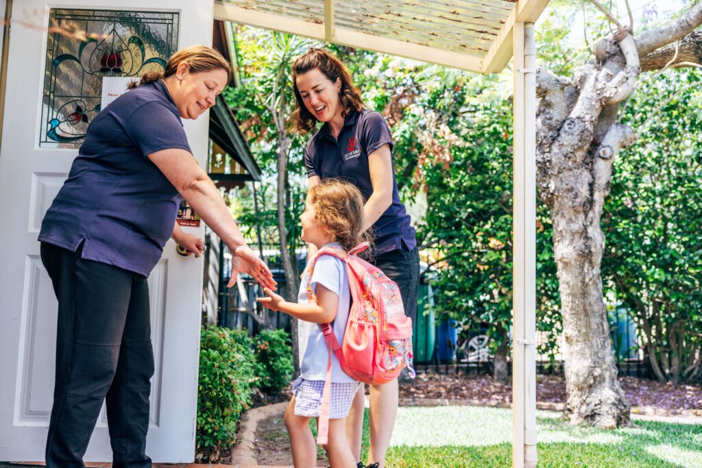 image showing a parent handing over a child to the daycare centre director at Care for Kindies.
