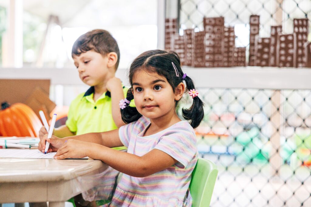 Preschool girl sitting at a table, listening.